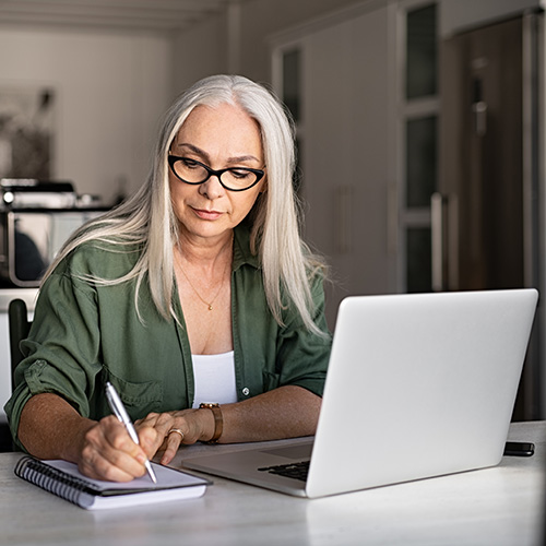 a doctor taking notes while sitting at a desk with their laptop