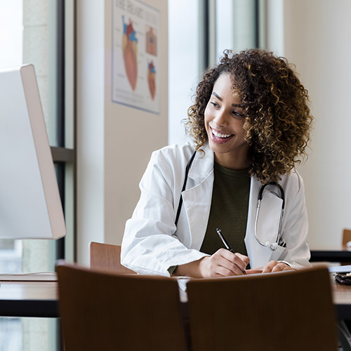 a doctor doing paperwork while referencing a DataDx report on their computer