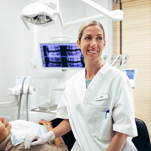 A dentist sitting with a patient whose x-rays are on the screen